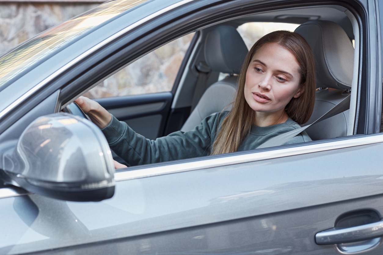 image of a woman looking pensively out her car