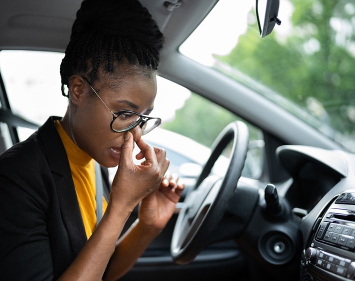 woman sitting in car holding her nose