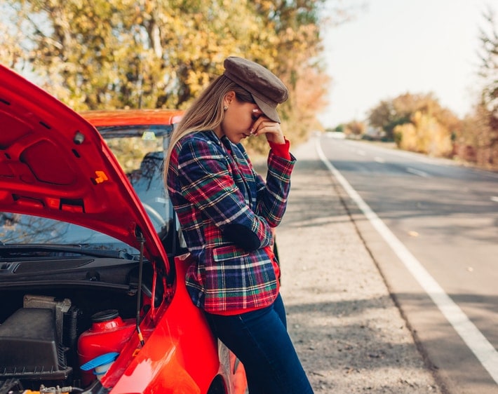 Woman leaning on a broken down car